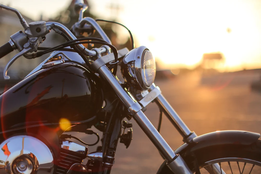 Chrome headlight and front forks of a motorbike at sunset — motorbike insurance